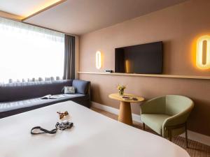 南希诺富特南希酒店的酒店客房配有床、沙发和电视。