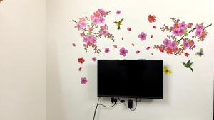 根尼亚古马里Tamizh Nest - தமிழ்க்குடில்的挂在墙上的平板电视,鲜花盛开