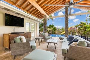 檀香山Tranquil Marina Front Pool House Resort的一个带家具和电视的庭院以及一个游泳池