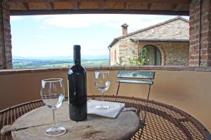 瓦尔的圣卡西亚诺AGRITURISMO VICOLABATE的一张桌子上摆放着一瓶葡萄酒和两杯酒杯