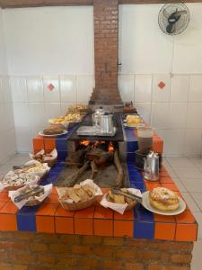 塞拉内格拉Pousada Fazendinha Alto da Serra的一张带壁炉、食物的桌子