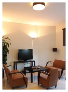 卡沃内拉斯三叶草酒店的客厅配有电视、2把椅子和1张桌子
