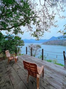 圣马科斯拉拉古纳El Castillo en el Lago Atitlán的木甲板上设有2张长椅,俯瞰着湖泊