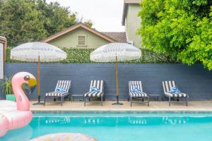 洛杉矶Angel&Rose Universal Hollywood Heated Pool House King Bed的一组椅子和遮阳伞,位于游泳池旁