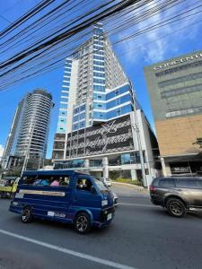 达沃市Davao City Serenity on Seventeenth One-Bedroom Condo beside Shopping Malls with Seaview and City view的一辆蓝色的面包车驶向城市街道,街道上有许多高大的建筑