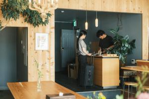 冈崎市Okazaki Micro Hotel ANGLE的办公室柜台上两名男子