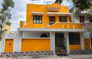 蒂鲁瓦纳马莱MPS Saai Residency的黄色房子的顶部设有阳台