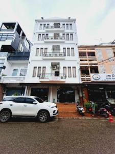 万象Sinakhone Vientiane Hotel的停在大楼前的白色汽车