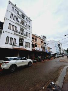 万象Sinakhone Vientiane Hotel的白色的汽车停在白色的建筑前