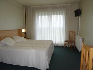 圣地亚哥－德孔波斯特拉阿克拉雷酒店的卧室配有床、椅子和窗户。