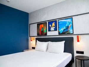 阿比让Ibis Styles Abidjan Plateau的酒店客房设有两张床,墙上挂有照片