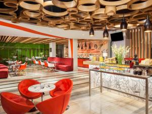 日惹ibis Yogyakarta Adi Sucipto的餐厅设有红色的桌椅和天花板