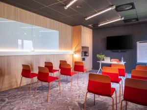 特雷利耶尔ibis budget Nantes Nord Treillières的一间会议室,配有红色椅子和屏幕
