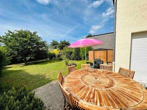 昂热Superbe maison spacieuse avec jardin的院子里的一张带粉红色伞的木桌