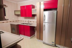 开罗The Villa 604 Powered by look的厨房配有红色橱柜和不锈钢冰箱