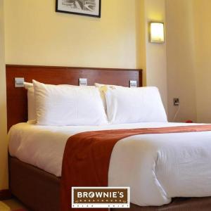纳库鲁Brownies Deluxe的配有白色枕头的床的酒店客房