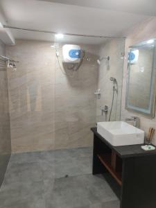 海得拉巴Grand Manor Suites的带淋浴、盥洗盆和镜子的浴室