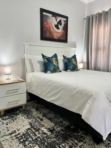 哈博罗内Sarona LoLa E206的卧室配有带蓝色枕头的大型白色床
