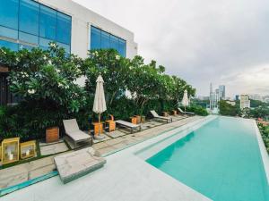胡志明市Serenity Saigon Sky Villas的一座大楼内的游泳池,配有椅子和遮阳伞