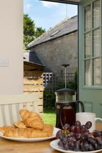 BarrasfordCosy Northumbrian Cottage的一张桌子,上面放两盘面包和葡萄