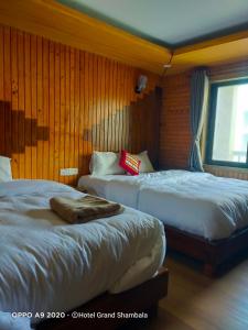 MuktināthHotel Grand Shambala的配有木墙和窗户的客房内的两张床