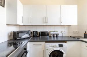 伦敦Stunning 1 bed flat in the heart of Greenwich的厨房配有白色橱柜、洗衣机和烘干机