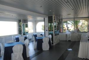 克罗托内太阳神酒店的一间设有桌子和白色椅子的房间,一间设有桌子的房间