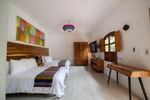 瓦哈卡市NaNa Vida Hotel Oaxaca的一间卧室配有两张床、一张桌子和一台电视。