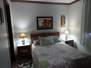 格拉玛多CASA DA FAMÍLIA DE GRAMADO的一间卧室配有一张床和两个带灯的床头柜