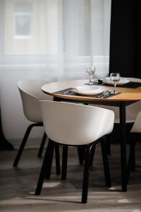 乌日霍罗德Luxury Apartments CITY的一张桌子、两把白色椅子和一张木桌及酒杯