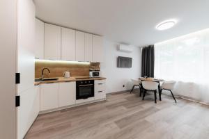 乌日霍罗德Luxury Apartments CITY的厨房配有白色橱柜和桌椅