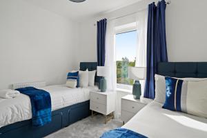 锡廷伯恩New Build 3 Bed House by AV Stays Short Lets Kent With Free Parking Ideal For Contractors的卧室设有两张床,配有蓝色窗帘和窗户