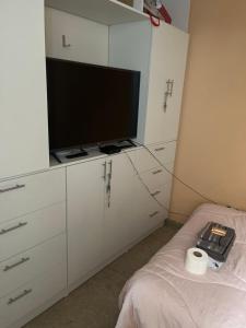 巴兰卡Alójate en una Casa familiar的一间设有白色橱柜、一台电视和一张床的客房