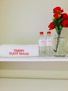 理查兹湾Pammy Guest House的一个带两瓶毛巾的架子和一个花瓶
