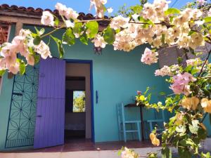 卡诺格布拉达Chalé Flor do ser的蓝色的房子,有紫色的门和鲜花