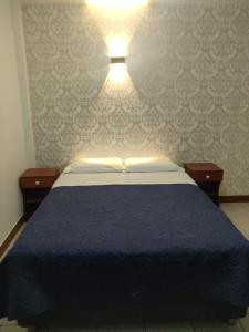 LambayequeLa Posada Norteña的一间卧室配有蓝色的床,墙上有灯