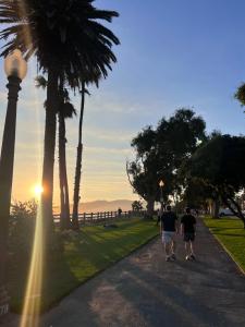 洛杉矶Cozy Santa Monica getaway steps to the beach Free Parking的两个人沿着棕榈树的道路走