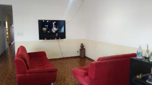 蒙加瓜pousada&Hostel perola mar的客厅配有2把红色椅子和电视