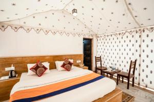 山姆Desert Safari Camp & Resort Sam的卧室配有一张床和一张桌子及椅子