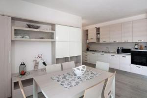 伦诺Appartamenti Zerboni的厨房配有白色的桌子和白色的橱柜。