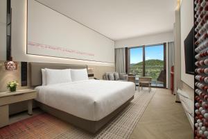 三亚三亚亚龙湾星华华邑度假酒店（首日迷你吧免费）的酒店客房设有一张白色大床和一张桌子。