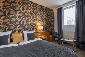 巴德加斯坦雷德酒店的一间卧室配有一张带花卉壁纸的大床