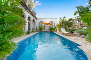 会安Maison Fleur Luxury Hoi An的棕榈树房子后院的游泳池