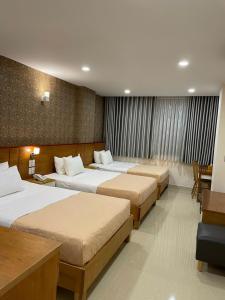 胡志明市Mia Hotel的酒店客房设有三张床和一张书桌