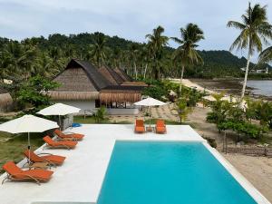 San IsidroYapak Beach Villas的毗邻度假酒店的带椅子和遮阳伞的游泳池