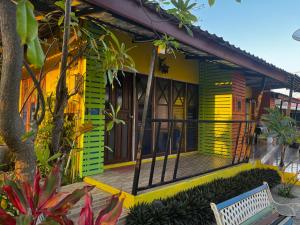 Ban Muang Baบ้านพักสิริ มุกดาหาร (Baan Siri Mukdahan)的黄色和绿色的房子,前面有长凳