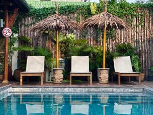 奈扬海滩绿纳 旅舍的一组椅子和遮阳伞,位于游泳池旁