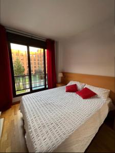 马德里Samaniego suite, AirPort, ifema turístico的一间卧室配有一张带两个红色枕头的床