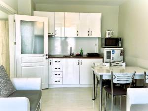 普里莫尔斯科Apartments Stamopolu Lux with pool view的厨房配有白色橱柜和桌椅