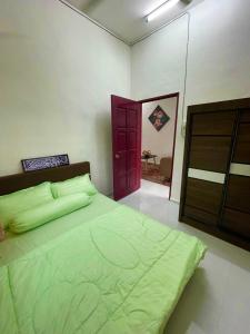 大山脚Tok Abah Homestay Bukit Mertajam的一间卧室设有一张绿色的床和一扇红色的门